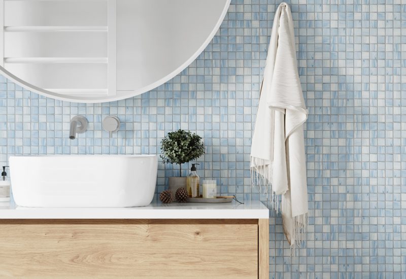 Bathroom with white and blue tiled walls, large white mirror and a shower. Scandinavian style