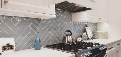 Peaceful kitchen design with light blue herringbone tile backsplash. Interior design and kitchen remodel