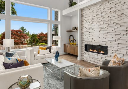 Remodeled living room with stone featured fireplace wall and large windows.
