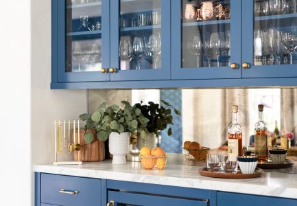 Blue kitchens cabinet with glass doors and white quartz countertops.