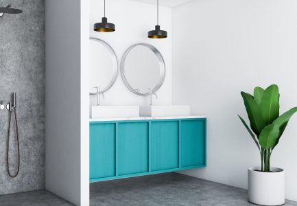 Turquoise wall vanity with round mirrors and walk in shower.